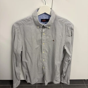 Rutig skjorta från Morris - Klassisk rutig skjorta från Morris i vitt och blått. Skjortan har lång ärm, knappar framtill och button-down krage. Liten broderad logga på bröstet. Perfekt för en stilren och avslappnad look.