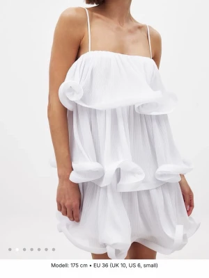 Vit volangklänning från NA-KD - Superfin vit kort klänning från NA-KD med tunna axelband och flera lager volanger. Klänningen har en luftig och flowy känsla, perfekt för varma dagar. Plisserad struktur ger extra stilpoäng och den är lätt att matcha med accessoarer.Nypris 799kr! helt oanvänd 