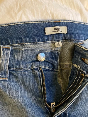 Blå relaxed baggy jeans från Bobby - Säljer ett par ljusblå relaxed baggy jeans från Bobby. Jeansen har klassisk femficksdesign, dragkedja och knapp i midjan. Tillverkade i denim med en lös och avslappnad passform som ger en cool och trendig look.
