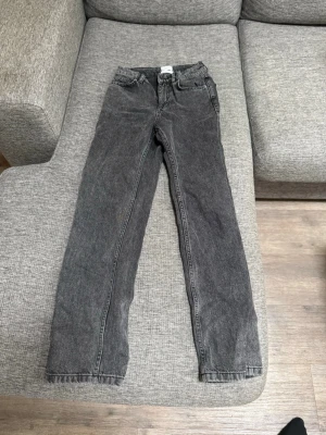Svarta raka jeans med tvättad look - Säljer ett par svarta jeans med tvättad vintage-look och raka ben. Jeansen har klassisk femficksdesign och normal midja. Materialet är denim i bomull och de har en avslappnad passform som passar till det mesta. Köpta på kids brand store från märket ”Grunt” och är i storlek xs. Bra skick.