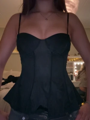 Svart korsett topp med tunna axelband - Snygg svart korsett topp! Jätte fin för en fest look 💗 Säljer för att den är för liten för min bröst storlek (75C-70D), men annars super fin och passar mig övrigt :) 
