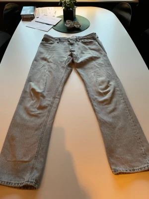 Ljusgrå raka jeans - Säljer ett par ljusgrå jeans från Jack and Jones  med rak passform och klassisk femficksdesigni storlek 32/34. Perfekta för dig som gillar en enkel och clean stil. Tveka inte att höra av dig om du undrar något.