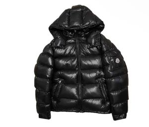 Svart pufferjacka från Moncler - Säljer en svart pufferjacka från Moncler med glansig finish och huva. Jackan har dunfyllning, dragkedja framtill och två sidofickor med dragkedja. Moncler-logga på ärmen och snygga detaljer vid axlarna. Perfekt för dig som vill ha en stilren och varm jacka.