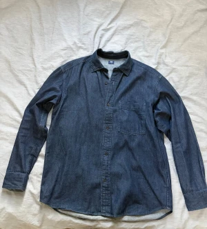 Denim overshirt från Uniqlo - Snygg washed denim overshirt från Uniqlo i klassisk modell med bröstficka och knappar framtill. Knappt använd alls. Storlek Small men pass även medium