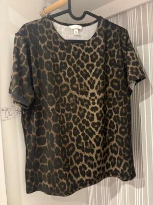 Leopardmönstrad idrotts t-shirt från H&M XL - Idrotts t-shirt från H&M i storlek XL med leopardmönster i svart och bruna toner. Klassisk rund halsringning och korta ärmar. Hanterar svett perfekt.