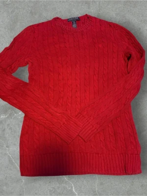 Röd kabelstickad tröja Lauren Ralph Lauren - Säljer nu en varm och riktigt fin tröja från Lauren Ralph lauren! Den är varm och skön och passar perfekt till vintern⛄️.    Skick 8/10 🌟.   Den är röd i färgen ❤️  Den är i storlek XS 🙌 (sitter nog exakt som xs men passar nog S också). Hör gärna av er vid fler funderingar 🤩