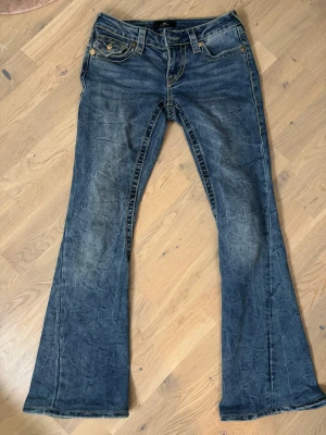True Religion blå bootcut jeans - Säljer lpgmidjade True religion jeans i Stl 24/32 insydda i midjan & längden är upplagd med original söm. Midja 38 cm rakt över, innerbens längd 80cm.  Passar en person med längd på 160-164cm.  Knappt använda nypris 1700 Pris nu 800kr