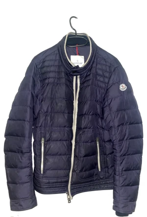 Mörkblå Moncler pufferjacka - Säljer en mörkblå pufferjacka i storlek 3 M från Moncler med quiltad design och vita detaljer vid dragkedjan och kragen. Jackan har två fickor med dragkedja och Moncler-logga på ärmen. Perfekt för dig som vill ha en snygg och varm jacka med exklusiv känsla. Finns äktahetsbevis! Pris ej hugget i sten!