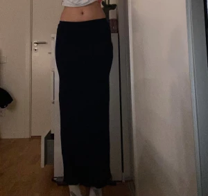 Mörkblå långkjol från Nelly XXS - Snygg mörkblå långkjol från Nelly i mjukt och stretchigt material. Kjolen har en rak och tight passform som sitter högt i midjan och ger en clean siluett. Perfekt att styla med crop tops eller hoodies för en chill vibe. Knappt använd