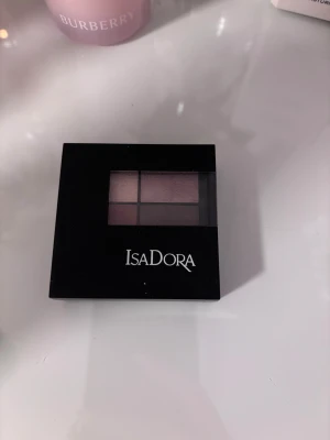 Isadora ögonskuggspalett nude shimmer - Säljer en snygg ögonskuggspalett från Isadora med fyra skimrande nyanser i nude, rosa, koppar och brun. Paletten har en stilren svart förpackning med genomskinligt lock och inbyggd spegel. Perfekt för att skapa både mjuka och intensiva looks.