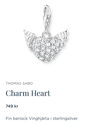 Silverfärgad vinge-hjärta armband Thomas Sabo - Säljer ett snyggt charm armband från Thomas Sabo med ett charmigt hjärta med vingar, täckt av glittrande stenar. Hängsmycket är i sterling silver 925s och kommer i en lyxig glitter ask med en rosa rosett. Säljer pga att jag fick den i present men tyvärr så föredrar jag guldiga smycken. Ej använd därav originalpris. Priset går självfallet att diskutera. 