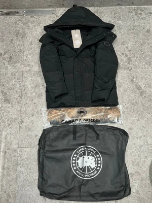 Canada Goose Wyndham Svart Label - Tja! Säljer nu min sprillans nya Canada Goose Wyndham jacka. Jackan är helt ny och oanvänd och säljs på grund av att jag köpt en annan jacka. Skriv privat vid minsta lilla fundering!