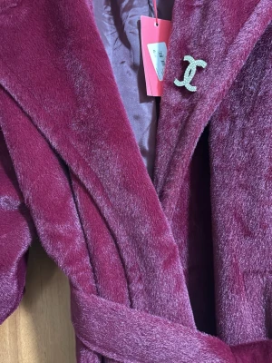 Vinröd lång pälsjacka med bälte. - Snygg och varm vinröd pälsjacka med bälte. Använd bara ett par gånger, i mycket fint skick. Passar perfekt till vintern och ser elegant ut både till vardag och fest.köper från turkiet , kan hämtas eller skicka 