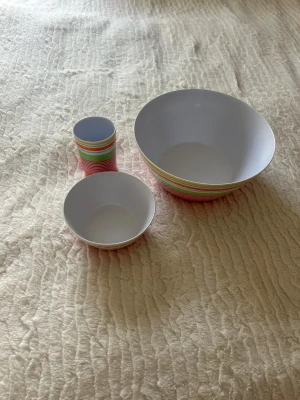 Randig väst i färgglad skålar i plast  - Säljer en färgglad väst med vita, gröna, rosa, orange och gula ränder. Västen har en klassisk passform  Perfekt för husvagn eller husbil 