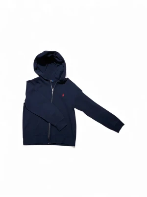 Polo Ralph Lauren hoodie - (Hoodien är knappt använd)Snygg marinblå hoodie från Polo Ralph Lauren med dragkedja och huva. Klassisk röd broderad logga på bröstet. Mjuk bomullskänsla och två fickor framtill. Perfekt för chill dagar eller när du vill ha en clean streetstyle. Köpt för 1000+ kr från kidsbrandstore. Storleken är 14-16 som motsvarar xs. Hör av dig om du har några frågor. Priset är prutbart via enkel affär