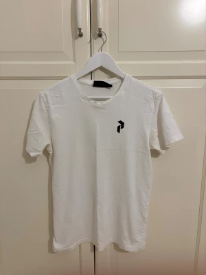 Vit t-shirt med svart grafiskt tryck - Snygg vit t-shirt med ett svart grafiskt tryck på bröstet och ett större tryck på ryggen. Klassisk rund hals och korta ärmar. Perfekt för dig som gillar minimalistisk stil och tydliga kontraster. Materialet känns mjukt och skönt mot huden.