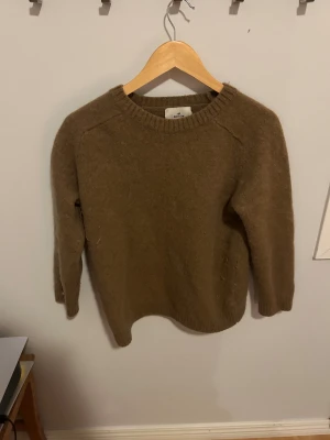 Brun stickad tröja från H&M Edition - Mysig brun stickad tröja från H&M Edition i storlek M. Tröjan har rund halsringning, ribbade muddar och lång ärm. Perfekt för lager-på-lager och chill höst- och vinterstil.
