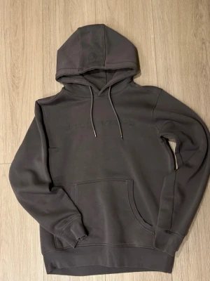 Mörkgrå Sail Racing hoodie - Snygg mörkgrå hoodie från Sail Racing med broderad logga på bröstet. Tröjan har huva med snörning, ribbade muddar och en stor magficka. Perfekt för dig som gillar stilrena och bekväma plagg med vibe. Mer bilder eller frågor är det bara att ge mig en signal svarar oftast inom 1-2 timmar och skickar samma dag om man beställer innan 19:00 