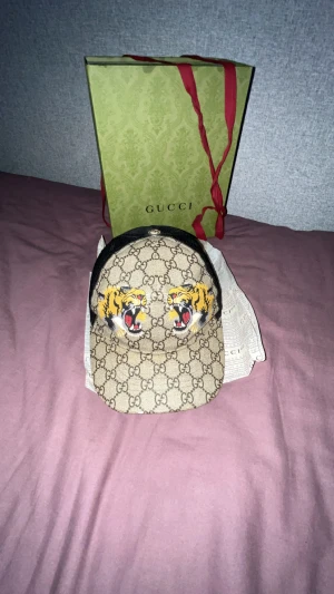 Äkta Gucci keps med tigertryck - Bege gucci keps med tigertryck den är som ny allt följs med som finns i bilden kostar. Passar till alla stilar 