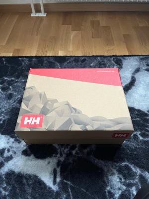 Helly Hansen bruna kängor med snörning - Snygga bruna kängor från Helly Hansen med grov sula och snörning i metallöglor. Skorna har en kombination av skinn och slitstark textil, samt HH-logga på sidan. Perfekta för höst och vinter när du vill ha både stil och funktion.