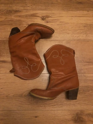 Cowboy boots - Snygga cowboy boots i en brun orange nyans med trä klack och spetsiga tår och rymliga. Ärvda men aldrig använda av mig. 