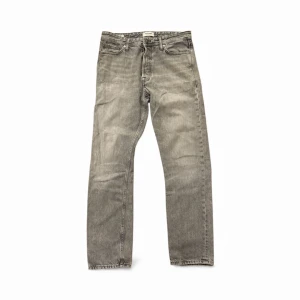 Grå loose fit jeans Jack & Jones - Snygga grå jeans från Jack & Jones i loose fit-modellen Chris. Klassisk femficksdesign, raka ben och normal midja. Jeansen är tillverkade i slitstarkt denim och har en cool tvättad look som passar perfekt till streetwear.