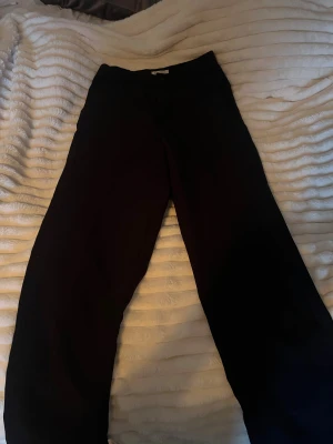 Svarta kostymbyxor från Lindex i xs - Stilrena svarta kostymbyxor från Lindex med klassisk rak passform och knappstängning i midjan. Storleken är 150 men sitter som XS! Perfekta för dig som gillar en clean look och vill ha ett par byxor som funkar till många olika outfits. Materialet är mjukt och har en lätt stretch. byxorna är lite noppriga (sista bilderna)