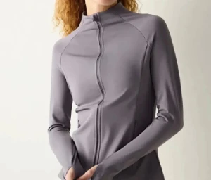 Grå zip-tröja med lång ärm - Snygg grå zip-tröja med lång ärm och hög krage. Tröjan har en slim passform och är tillverkad i ett mjukt syntetmaterial som passar perfekt för träning. Dragkedjan framtill gör den enkel att ta på och av. Stilren och sportig look.