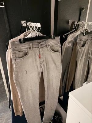 Grå ” Dsquared2 ”  jeans   - Snygga grå jeans från Dsquared2 med slim fit och slitna detaljer. Jeansen är i stretchigt denim och passar dig som vill sticka ut lite. Byxorna är i mycket bra skick! Läderpatchen har tappat lite färg, se på bild 3.