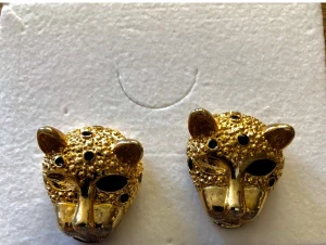 Guldiga leopardörhängen - Unika örhängen i form av leopardhuvuden med guldig finish och svarta detaljer för ögon och fläckar. Djurinspirerad design som sticker ut och ger en cool touch till din stil. Perfekt för dig som gillar statement-smycken och djurmönster.