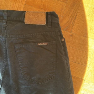 Svarta jeans från Marlboro Classics - Svarta jeans från Marlboro Classics med klassisk femficksdesign och raka ben. Byxorna har snygga detaljer som metallknapp och läderpatch bak i midjan. Materialet är robust bomull med en skön känsla och passformen är normal. Perfekta för en stilren och avslappnad look. Högra bakbenet har tecken av användning. 