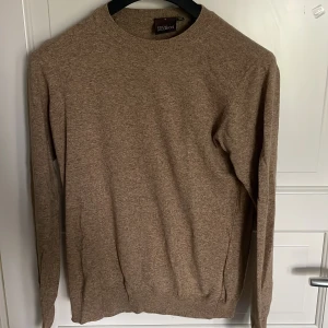 Beige stickad tröja Oscar Jacobson - Snygg beige stickad tröja från Oscar Jacobson i klassisk modell. Tröjan har rund halsringning och långa ärmar, perfekt för lager-på-lager. Tillverkad i mjukt material som känns skönt mot huden. Enkel att matcha med jeans eller chinos.