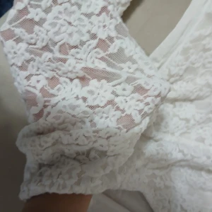 Vit blus från Amisu - Supersöt vit blus från Amisu med långa ärmar i blommig spets. Blusen har en figurnära passform och är perfekt för dig som gillar romantiska detaljer. Spetsen ger en extra touch och gör den riktigt unik.