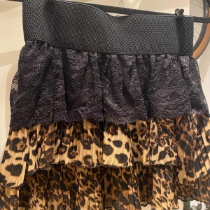 Leopardmönstrad volangkjol med spets - Snygg kortkjol med bred svart resår i midjan, svart spets upptill och flera lager volanger i leopardmönster. 💕💕💕