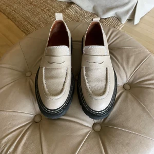 Chunky beige loafers i skinn - Snygga chunky loafers i beige skinn med grov svart sula och markerade sömmar. Klassisk penny loafer-design med modern twist och rund tå. Perfekta för dig som vill ha en stilren men edgy look. Aldrig använda, bara provade på 🩷