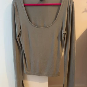 Ljus grön långärmad topp med rund ringning - Passar som S Säljer en stilren ljus grön långärmad topp med djup rund ringning. Toppen är i mjukt och stretchigt material, perfekt att matcha med jeans eller kjol. Enkel design utan mönster eller detaljer, vilket gör den lätt att styla till olika looks.