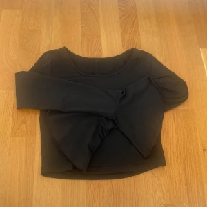 Svart croppad långärmad topp - Snygg svart croppad topp med långa ärmar och rund halsringning. Enkel och stilren design som passar perfekt till jeans eller kjol. Mjuk och stretchig känsla för en bekväm passform.