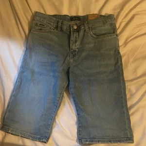 Blå jeansshorts Polo Ralph Lauren - Shortsen är inte använda som man ser på bilden se sitter fortfarande saker kvar från butiken som jag inte har dragit av. Snygga ljusblå jeansshorts från Polo Ralph Lauren, modell The Sullivan Slim. Klassisk femficksdesign, låg stretch och normal passform. Perfekt längd som slutar strax ovanför knäna. Stilsäkra och bekväma för sommarens alla dagar.