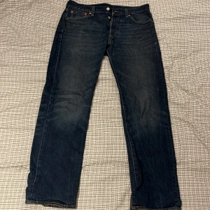 Levi's 501 jeans mörkblå 30/30 - Klassiska Levi's 501 jeans i mörkblå tvätt med raka ben och knäppning framtill. Jeansen har fem fickor, och den ikoniska läderpatchen bak i midjan. Perfekta för dig som gillar tidlös denimstil.