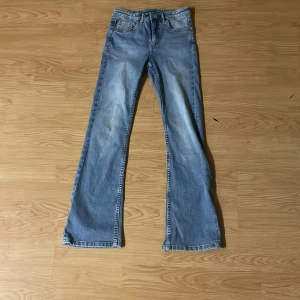 Ljusblå bootcut jeans från Kappahl - Säljer ett par ljusblå jeans från Kappahl i storlek 152. Jeansen har bootcut-modell med klassisk femficksdesign och snygga slitningar framtill. Perfekta för dig som gillar en avslappnad och trendig look.