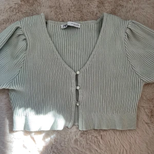 Ljusgrön ribbad bolero från Zara - Superfin ljusgrön ribbad bolero från Zara med korta puffärmar och v-ringning. Den är croppad och har snygga knappar framtill. Perfekt att styla med höga jeans eller kjol för en trendig look. 💘Använd 1 gång och köpt på Vinted🫰🏼