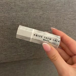 Läppstift från Give Them Lala Beauty - Snyggt läppstift med marmormönstrad vit hylsa och en varm nude-brun färg. Perfekt för dig som gillar naturliga toner och vill ha ett stilrent smink i väskan. Läppstiftet har en klassisk form och känns lyxigt med sin unika förpackning. Aldrig använd!