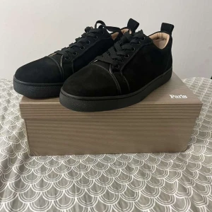 Svarta sneakers från Christian Louboutin - Stilrena svarta sneakers från Christian Louboutin i mocka med svarta snören och rund tå. Skorna har en klassisk siluett och diskreta detaljer, perfekt för dig som gillar lyxiga och minimalistiska vibes. Kommer med originalkartong och dustbags.