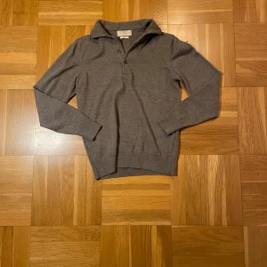 Grå ullpiké från The Tailoring Club - Riktigt skön ullpiké med knappar, tröjan är i storlek S men är liten i storleken och passar nog mer XS om inte mindre än det. Nypris runt 999kr, vårt pris endast 199kr! Priset är inte hugget i sten!