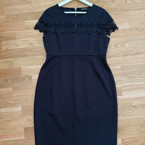 Säljer Marinblå klänning Dorothy Perkins! - Klänningen är som helt ny och endast använd ett fåtal gånger. Storlek: 44 Snygg marinblå klänning från Dorothy Perkins med blommig spetsdetalj över axlar och bröst. Kortärmad och figurnära passform med rund halsringning och dragkedja i ryggen. Perfekt för dig som gillar stilrena och feminina plagg.