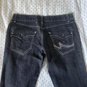 Lowwaist jeans - Jeans som är lowwaist och sydda bootcut. Glittriga i tyget och men coola bakfickor. Midjemått: 40 cm Innebenslängd: 82 cm