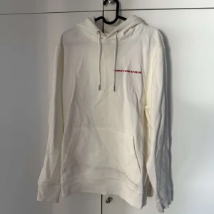 Vit hoodie Victor Leksell körsbär - Vit hoodie från Victor Leksell med röd text på bröstet och stort körsbärstryck på ryggen. Klassisk känguruficka, huva med snörning och mjukt material. Perfekt för dig som gillar snygga och unika merch-plagg. Endast använd en kväll. 