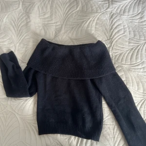Svart offshoulder stickad tröja SHEIN - Säljer en svart stickad offshoulder-tröja från SHEIN i storlek S. Tröjan har bred ribbad kant upptill och långa ärmar. Perfekt för dig som vill ha en stilren och trendig look med en twist.
