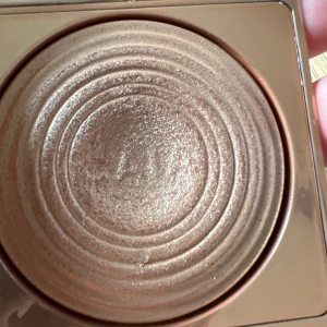 CAIA Highlighter Portofino - Säljer en CAIA highlighter i nyansen Portofino. Kommer i en snygg, guldig kompakt med spegel. Highlightern har en skimrande, champagnefärgad ton och pressad cirkelmönstrad yta. Perfekt för att ge glow till kindben, näsa och amorbåge. 