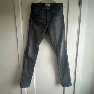Grå jeans från Jack & Jones, 29/34 - Snygga grå jeans från Jack & Jones i klassisk femficksmodell. Jeansen har en rak passform och normal midja, tillverkade i mjukt denimtyg. Perfekta för dig som gillar en stilren look med lite tvättade detaljer.